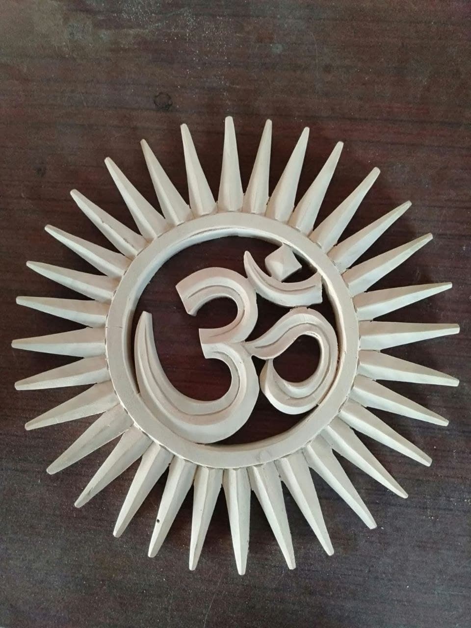 Hand-carved wooden Om medallion with sunburst border