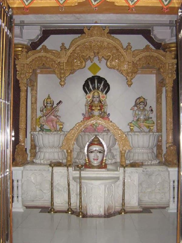 Ornate hand-carved wooden mandir with arched canopy
